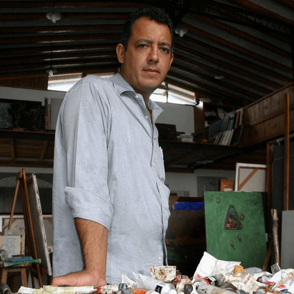Jesús Guerrero en plano tres cuartos posando en su taller con los materiales que utiliza para pintar