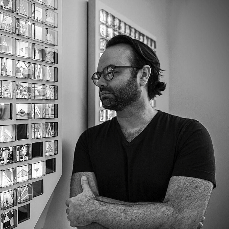 Foto de Richard Conti en blanco y negro posando junto a una de sus obras